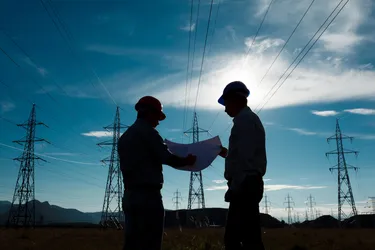 silhouette-of-two-engineers-standing-at-electricity-station-discussing-plan-222500491